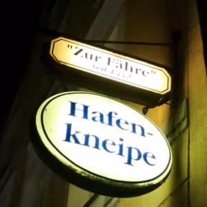Beleuchtetes Schild der Hafenkneipe „Zur Fähre“ in Stralsund bei Nacht. Das Songcover von MaiP Jorgenson vermittelt maritimes Flair, Heimat und norddeutsche Atmosphäre.